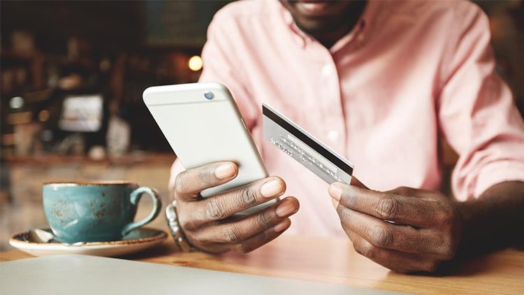 Man holding a phone and a debit card
